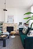 Living room with dark green velvet sofa and marble fireplace