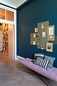 Hallway with purple upholstered bench and pin boards on dark blue wall