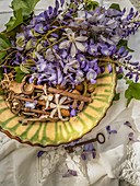 Clematis, wisteria, vintage keys and almonds in ceramic bowl