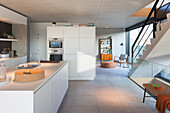Moderne Küche mit Kochinsel und Blick auf das Wohnzimmer mit Treppe