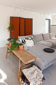 Bright living room with grey corner sofa and rustic wooden table