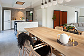 Großer Holztisch und Rattanstühle in offener Küche mit Marmortheke