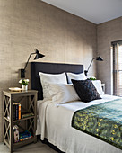 Bed with headboard against grey-brown wall in elegant bedroom