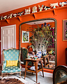 Peacock feathers in front of mirror in classic living room with orange wall