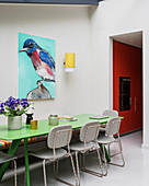 Green dining table and picture of bird in dining room with open doorway leading into kitchen