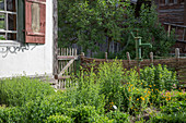 Bauerngarten mit Schwengelpumpe und Zaun aus Flechtwerk