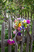 Rusty kitchen utensils decorating garden fence and bouquet in old funnel