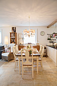 Dining table and open-plan kitchen in large, country-house-style interior