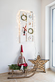 Weihnachtlich dekorierter Rahmen überm Holzschlitten mit Stoffzwerg
