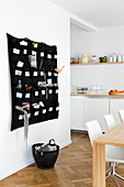 Fabric organiser on wall behind dining table in open-plan kitchen