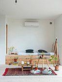 Eingebaute Sitzbank aus hellem Holz, Coffeetable, Hocker als Teetisch und Zimmerpflanzen im Wohnzimmer