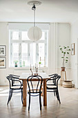 Black bistro chairs around dining table in period interior with panelled walls