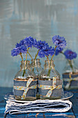 Cornflowers in small bottles with decoration