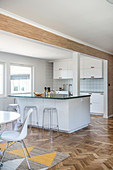 White, open-plan kitchen in modern interior with parquet floor