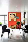 Picture on red wall in modern dining room with black dining table and chairs