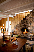 Open fireplace in wall clad in boulders in country-house-style living room