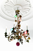 Colourful fairy lights wrapped around pretty chandelier hanging from ceiling rose