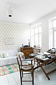 Chairs around old folding table in living room with polka-dot wallpaper