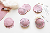 Embroidering pink, felt Christmas tree decorations with patterns