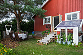 Falu-red wooden house with lean-to greenhouse and summery garden