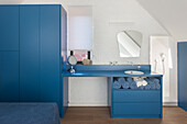 Blue washbasin with mirror and blue cabinets in the attic bathroom