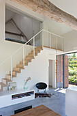Modern staircase with wooden steps and glass banisters in a bright room