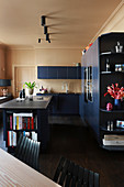 Dark blue, modern kitchen with dark floor and beige walls