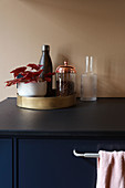 Begonia and kitchen utensils on golden tray in kitchen