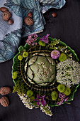 Artichokes, chrysanthemums, blue throatwort, waxflower, clematis and eucalyptus in bowl