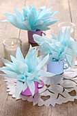 Handmade table decorations made from napkin flowers in coloured enamel cups