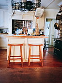 Bar stools at kitchen island below pans in rack