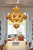 Modern chandelier of golden spheres above dining table in period building