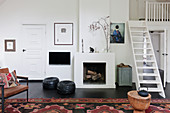 Ledersitzmöbel vor Kamin im Wohnzimmer mit Leitertreppe zur Galerie