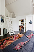 Sofa and Oriental rug in living room with ships' ladder stairs leading to gallery
