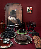 Bird portrait on tray and buffet of cakes on red table against red wall