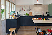 Kitchen with light-colored wall tiles, dark base cabinets and wooden elements