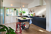 Moderne Küche mit Kochinsel, schwarzen Fronten und Holzboden