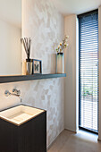 Modern guest bathroom with wall-mounted washbasin and geometric wallpaper