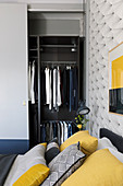 Open wardrobe in grey bedroom with yellow accents