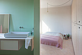 Minimalistisches Schlafzimmer mit Einbauschrank und Badezimmer mit hellgrüner Wand