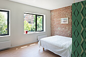 Minimalistisches Schlafzimmer mit Backsteinwand und grünem Raumteiler