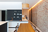 Küche mit Backsteinwand, Holztisch, Stühlen und hängender Pendelleuchte