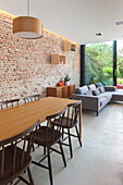 Dining area with wooden table and chairs, brick wall and adjoining living area