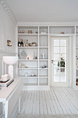 Fitted shelving surrounding door in classic, white living room