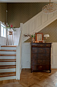 Antique chest of drawers in foyer with staircase and panelled wainscoting