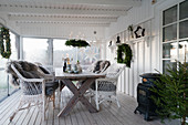 Wooden table and wicker armchairs on festively decorated veranda