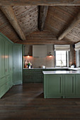 Country-house kitchen with green panelled cabinets in log cabin
