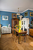 Esszimmer mit antiken Möbeln, blauen Wänden und Fischgrätparkett