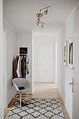 Coat rack, shell chair and rug in bright foyer