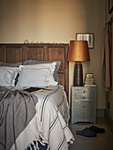 Doppelbett mit Bettkopfteil aus Eichenholz, daneben Nachtkästchen und Lampe